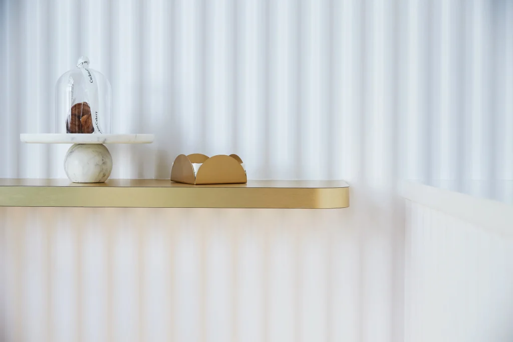 Interior Design - A decorative cake display featuring a glass dome and a gold-accented cake stand on a shelf. Dexign Matter Studio