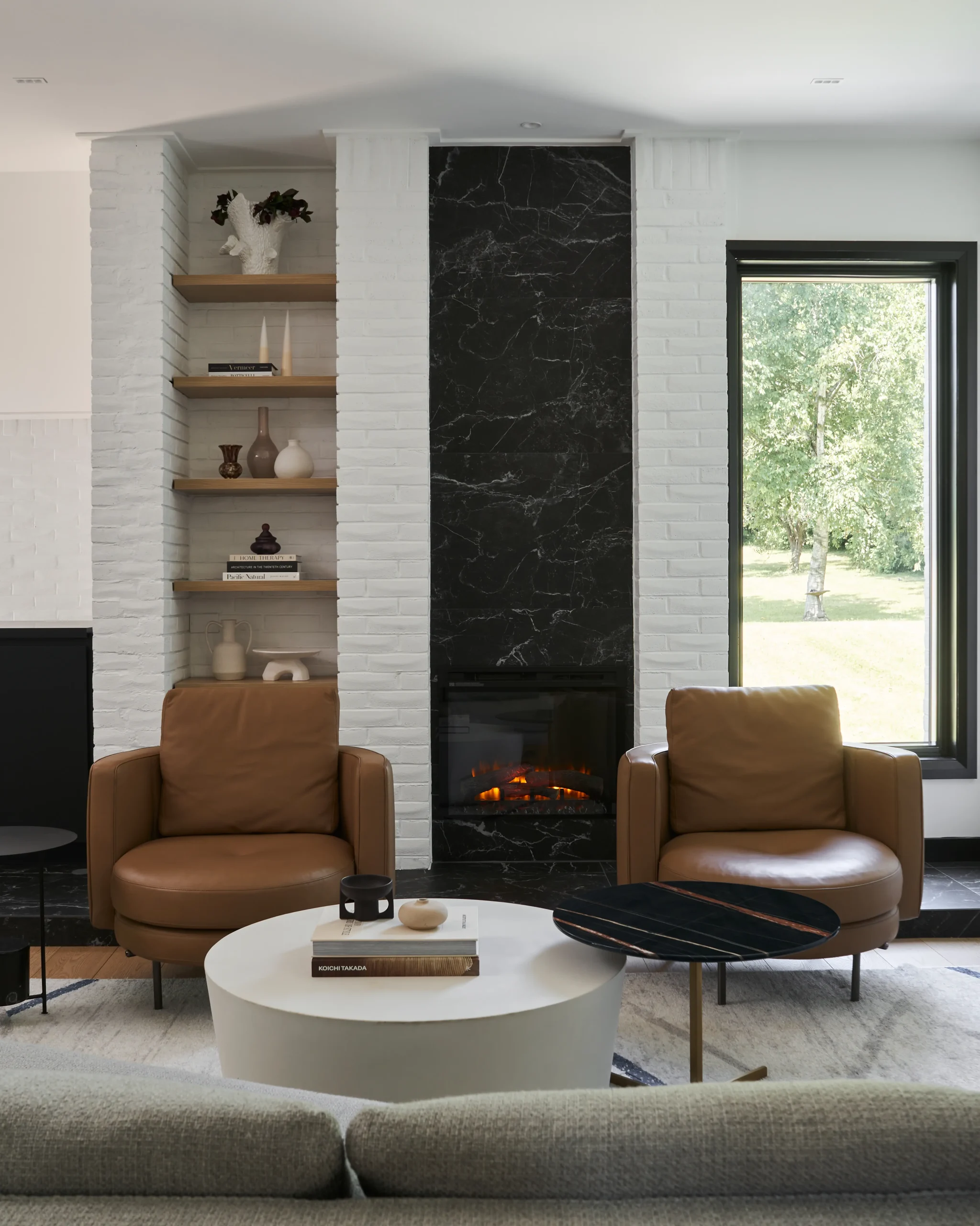 Interior Design - Contemporary living room featuring two brown leather chairs and a black marble fireplace. Dexign Matter Studio