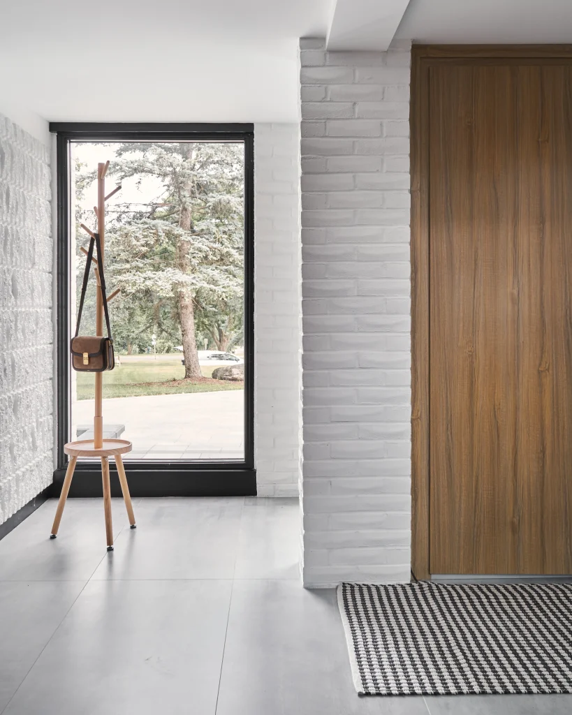 Interior Design - Interior view of an entryway featuring a wooden door and a coat rack with a bag. Dexign Matter Studio