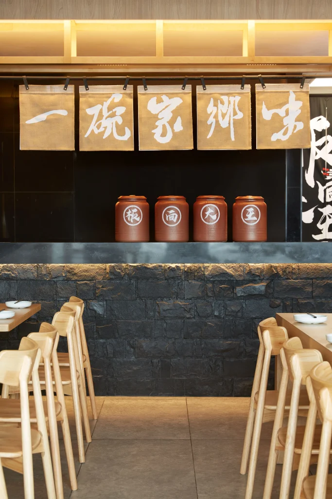 Interior Design - Interior view of a restaurant featuring wooden chairs and decorative jars on a shelf. Dexign Matter Studio