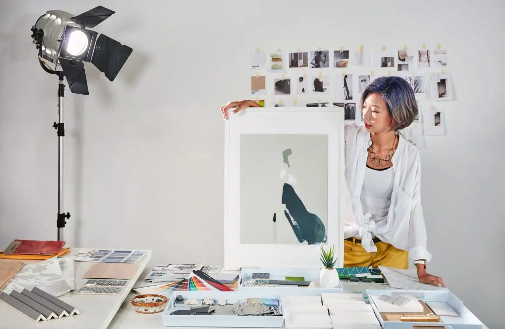 Interior Design - Interior designer displaying a large artwork while surrounded by design samples and materials. Dexign Matter Studio