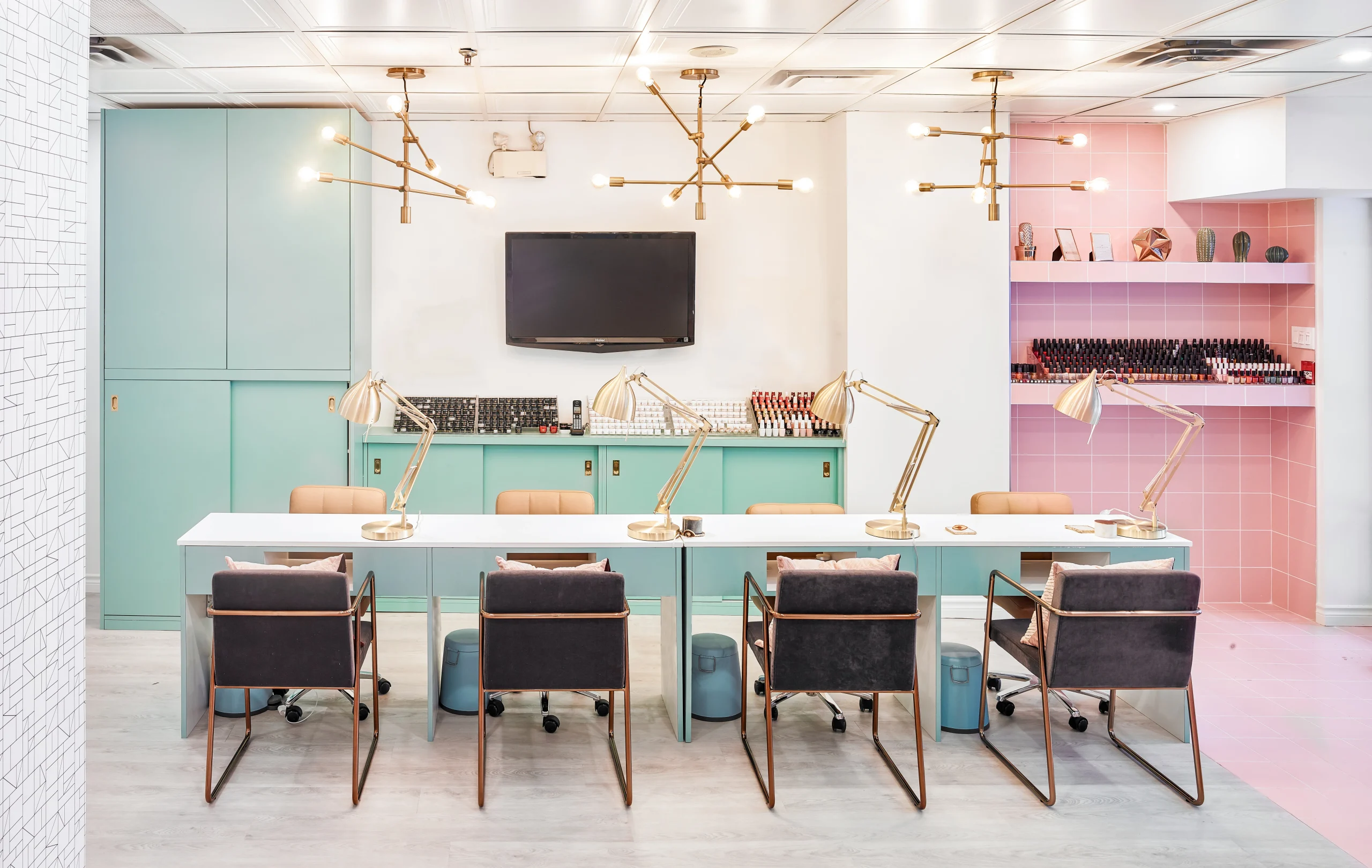 Interior Design - Interior view of a nail salon featuring workstations with lamps and a television on the wall. Dexign Matter Studio