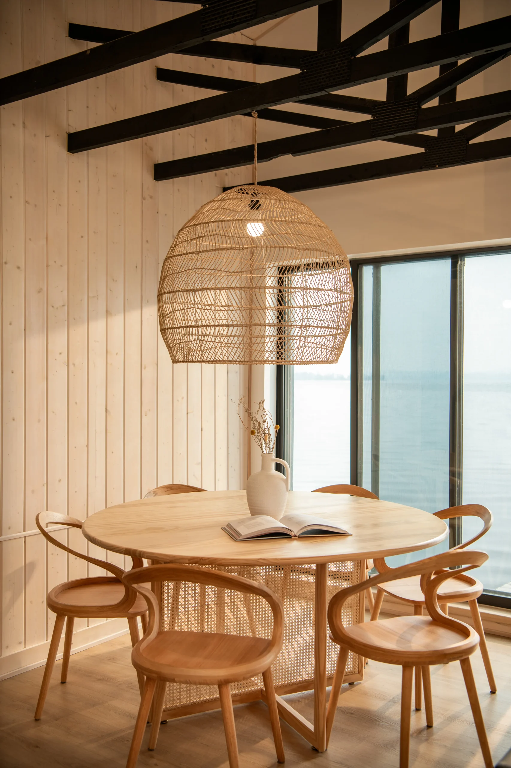 Interior Design - Round wooden dining table surrounded by rattan chairs under a woven pendant light. Dexign Matter Studio