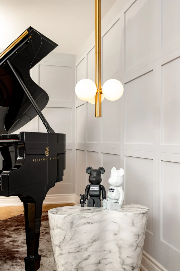 Interior Design - Steinway & Sons grand piano beside Bearbrick figures on a marble table. Dexign Matter Studio