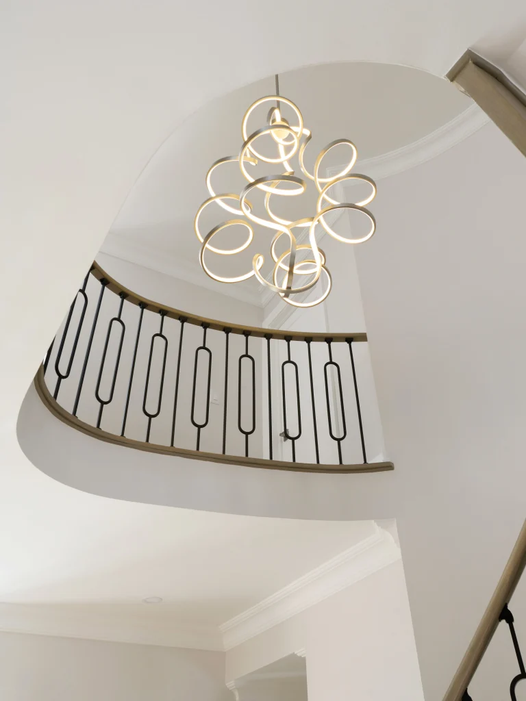 Interior Design - A modern chandelier with a unique design hanging from the ceiling above a staircase. Dexign Matter Studio