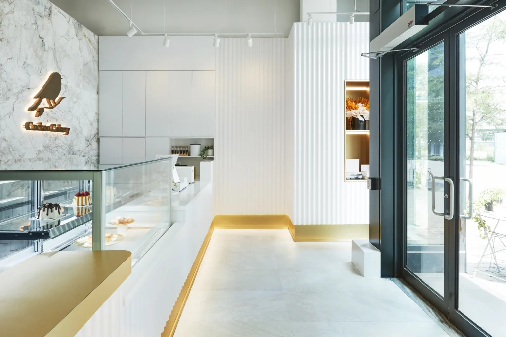 Interior Design - Interior view of a modern bakery with a glass display case and sleek design elements. Dexign Matter Studio