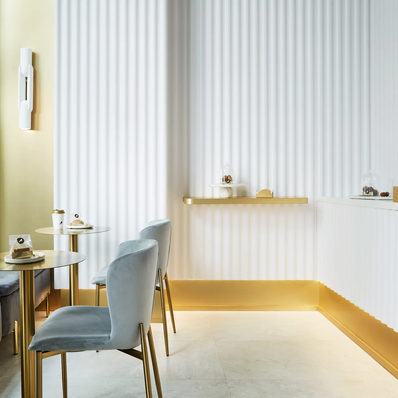 Interior Design - Interior view of a modern café featuring gold accents and textured white walls. Dexign Matter Studio
