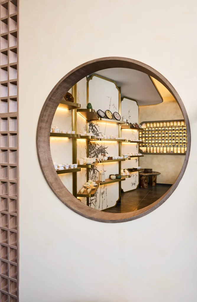 Interior Design - A circular wooden mirror reflecting a display of tea products in a shop interior. Dexign Matter Studio