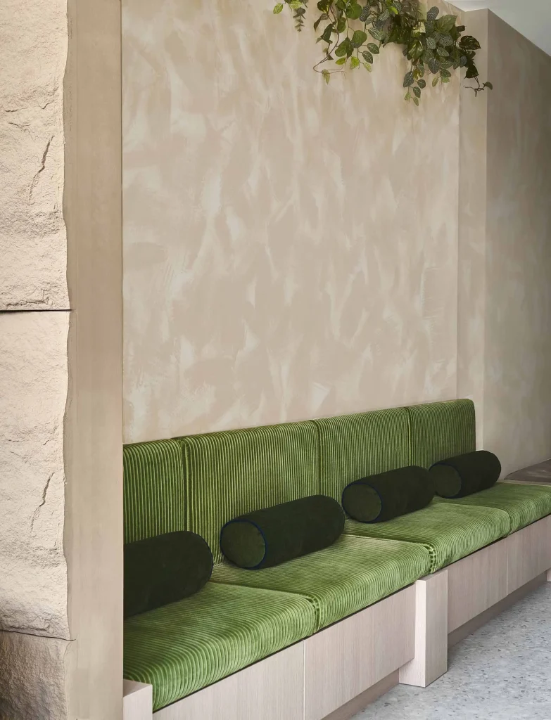 Interior Design - Green upholstered bench with round cushions against a textured wall. Dexign Matter Studio