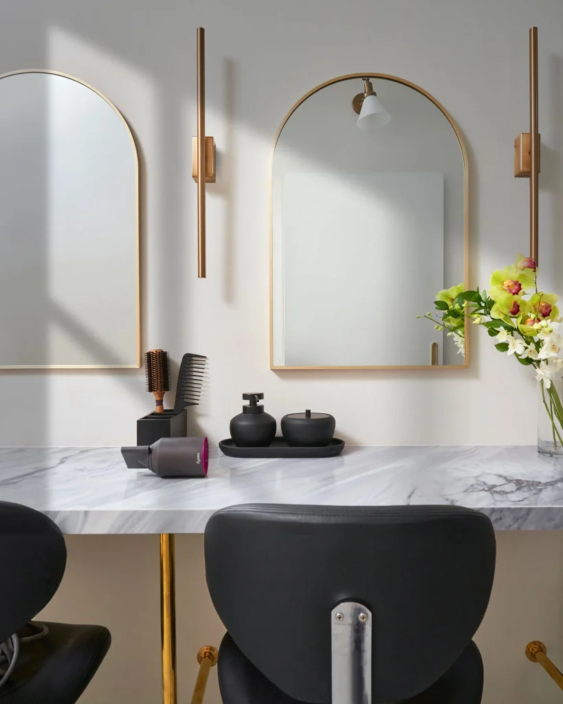 Interior Design - Interior view of a hair spa featuring two mirrors, a marble countertop, and a floral arrangement. Dexign Matter Studio