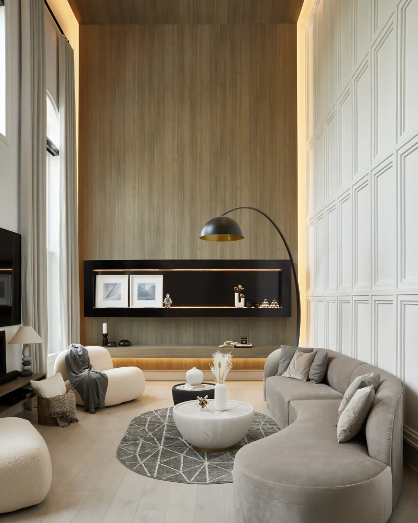 Interior Design - Contemporary living room featuring a curved sofa, round coffee table, and decorative elements on a shelf. Dexign Matter Studio