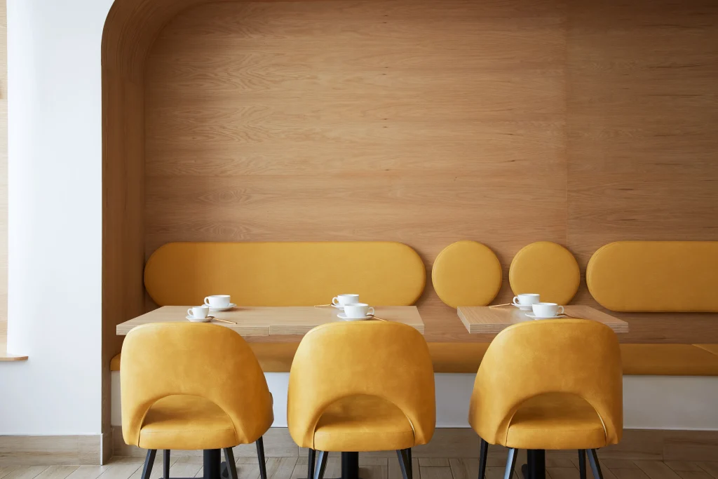 Interior Design - Three yellow upholstered chairs at a table with white cups in a modern interior design. Dexign Matter Studio