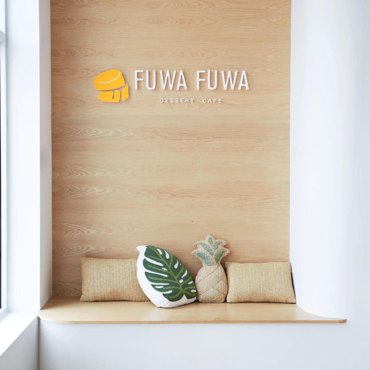 Interior Design - Interior view of Fuwa Fuwa Dessert Cafe featuring a wooden wall and decorative cushions. Dexign Matter Studio