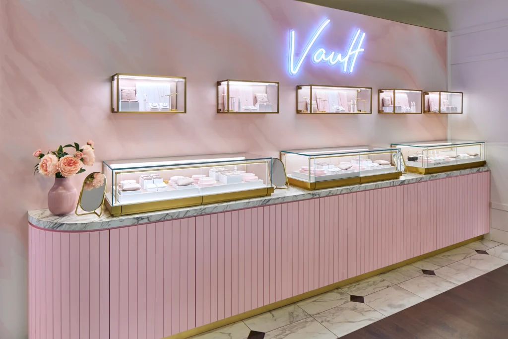 Interior Design - Jewelry display case featuring glass showcases and a pink accent wall with the word 'Vault' in neon. Dexign Matter Studio
