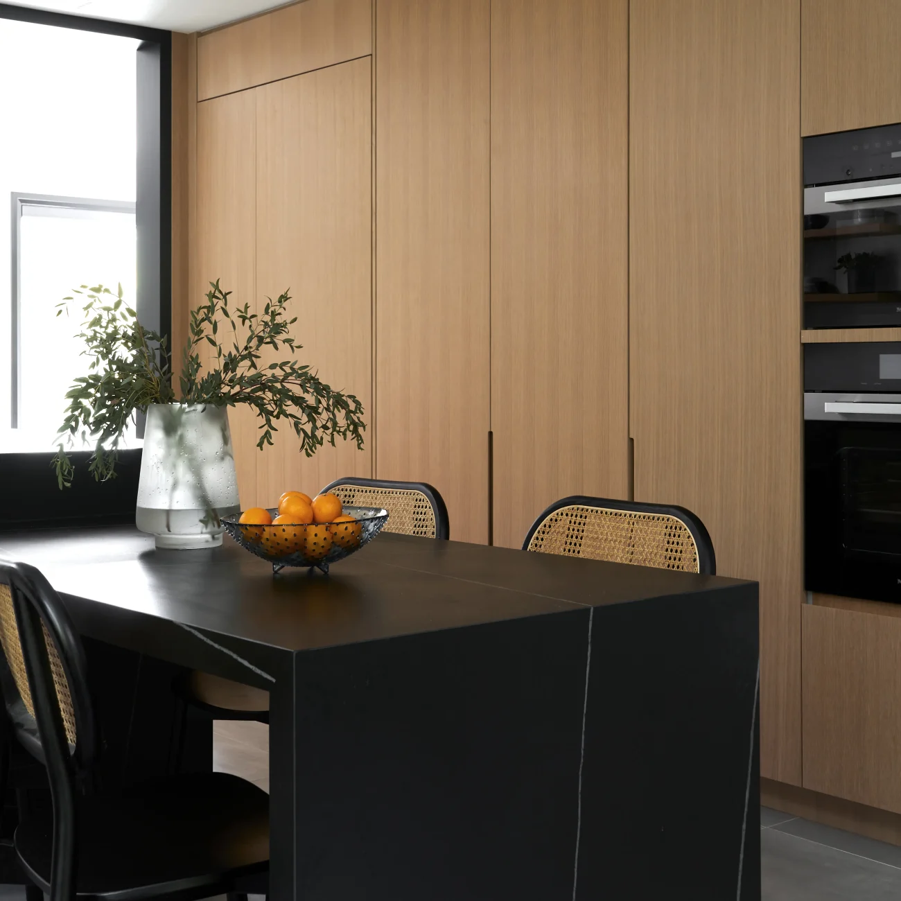 Interior Design - A modern kitchen counter featuring a black surface and a bowl of oranges. Dexign Matter Studio