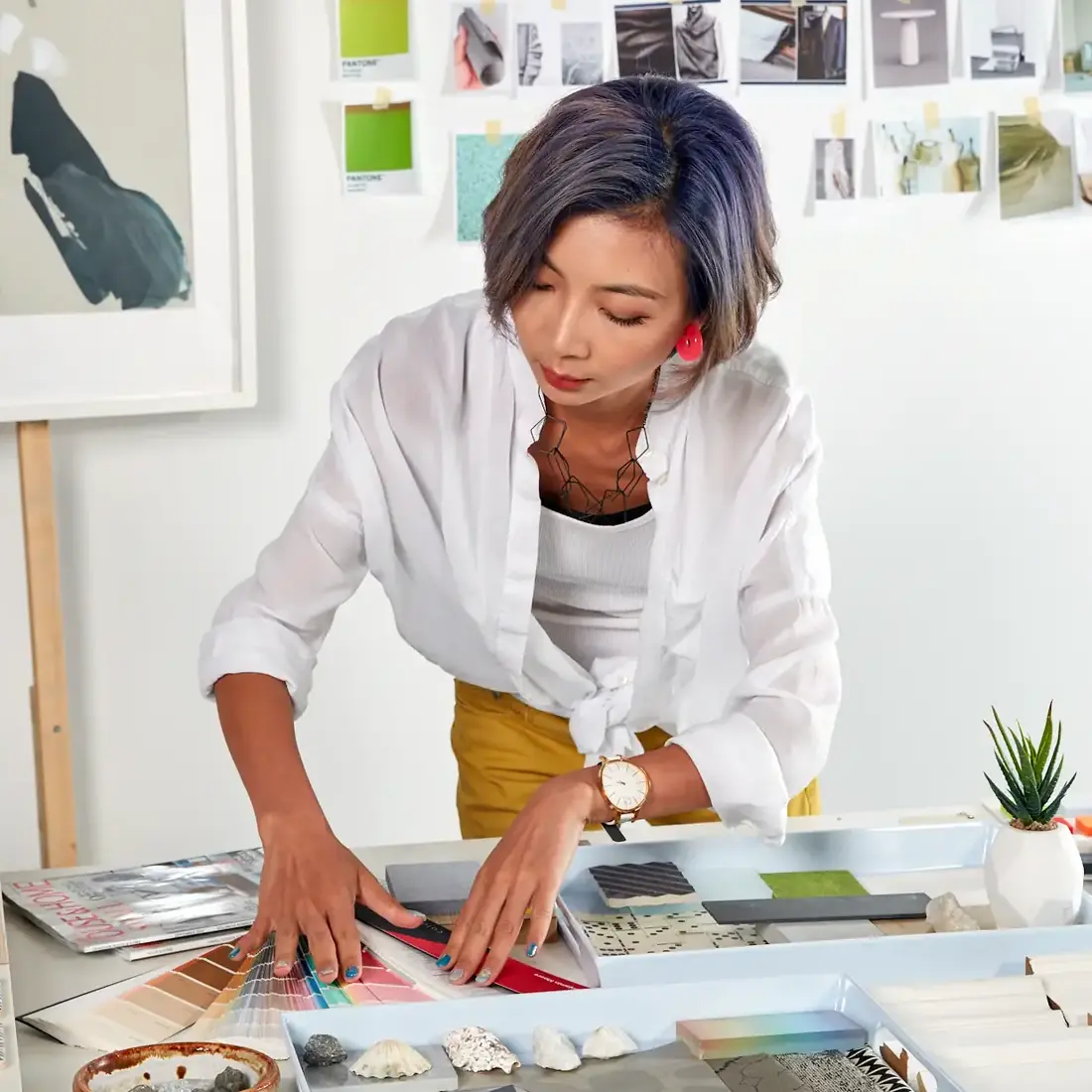 Interior Design - Interior designer arranging color swatches and materials on a table in a studio setting. Dexign Matter Studio