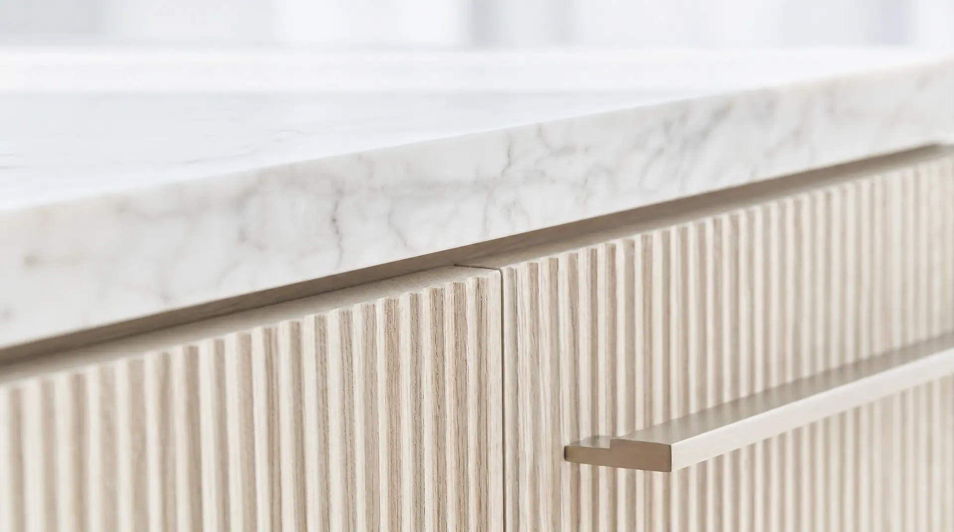 White marble ledge and brass handle meet vertical wood slats in tactile luxury commercial interior design.