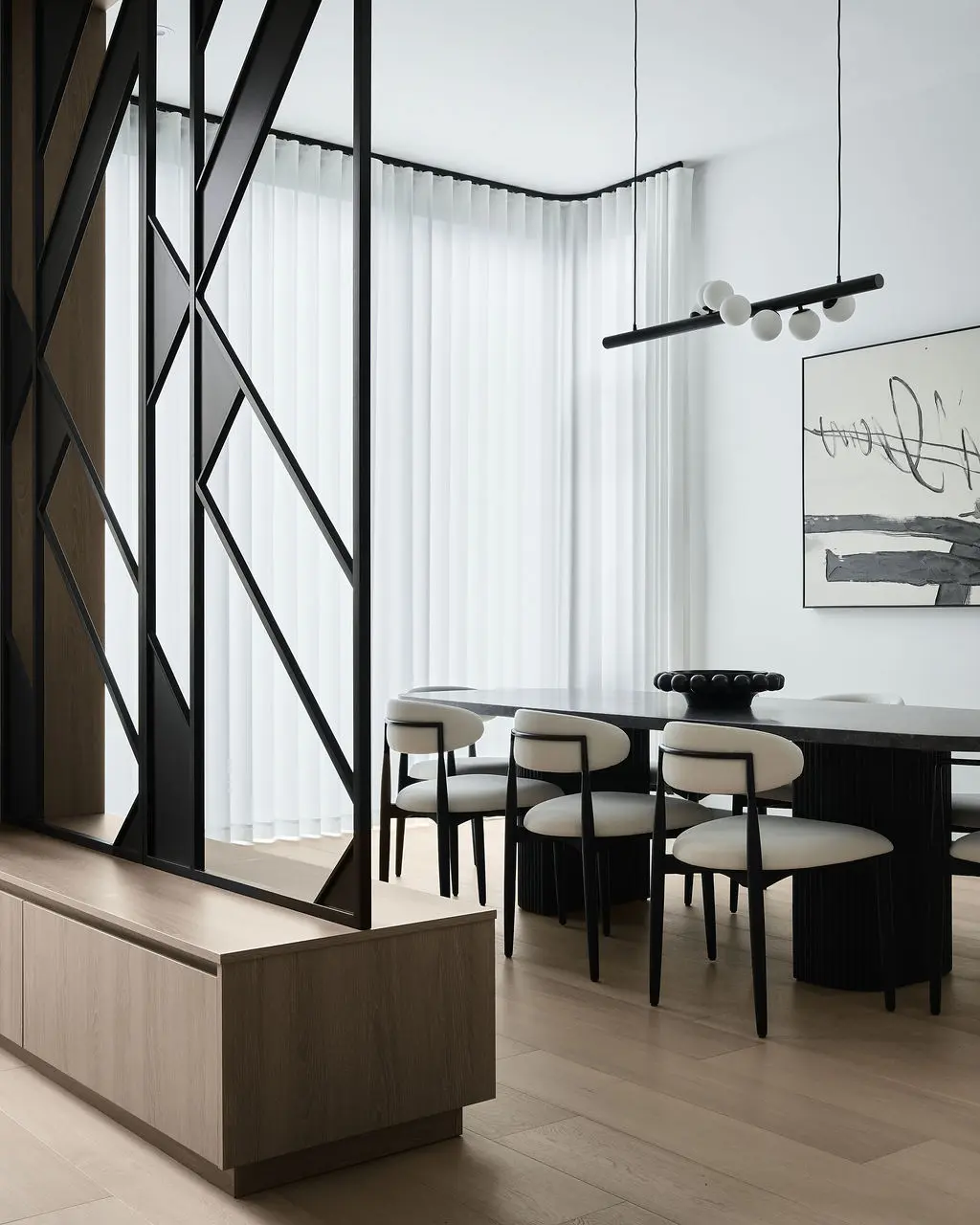 Interior Design - A modern dining room with black-framed partition panels, white upholstered chairs, a long dark table, and sheer curtains. Dexign Matter Studio