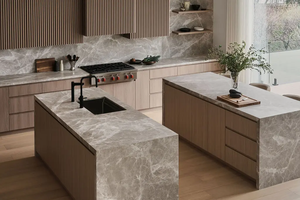 Interior Design - Modern kitchen with twin marble islands, pale wood cabinetry, a black faucet, and a large window wall with daylight. Dexign Matter Studio
