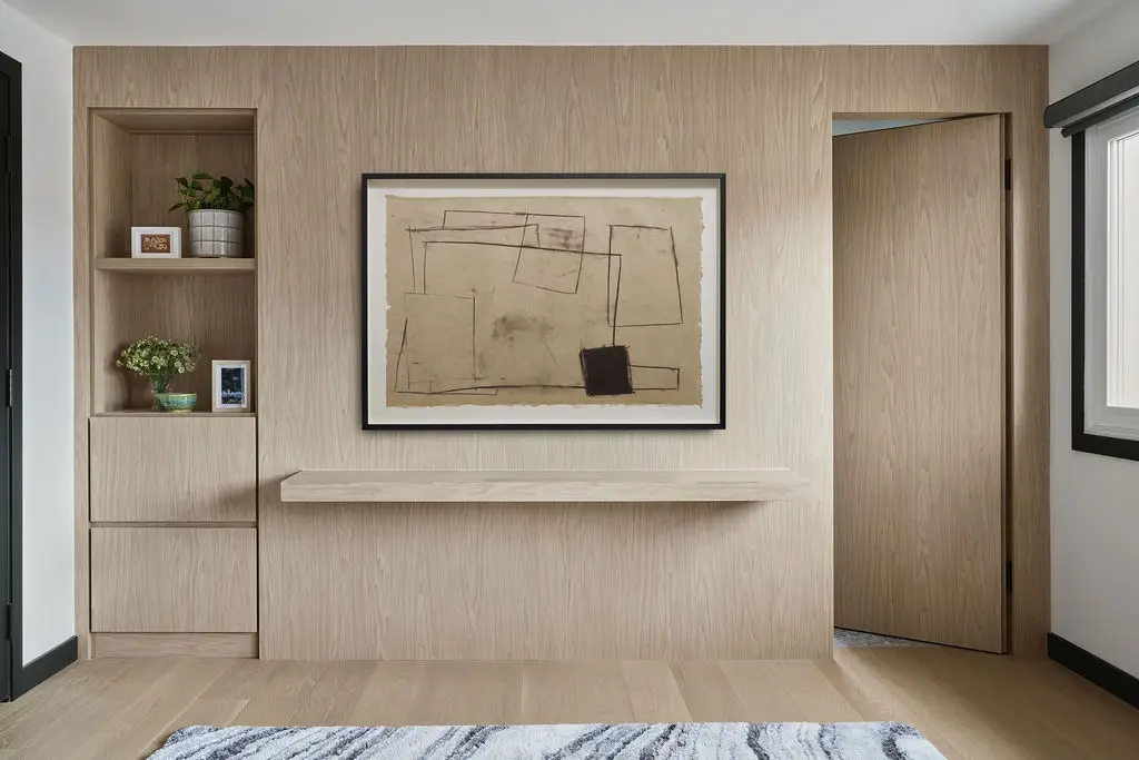 Interior Design - A light wood accent wall frames abstract artwork, open shelving, and a built-in ledge beside a partially open doorway. Dexign Matter Studio