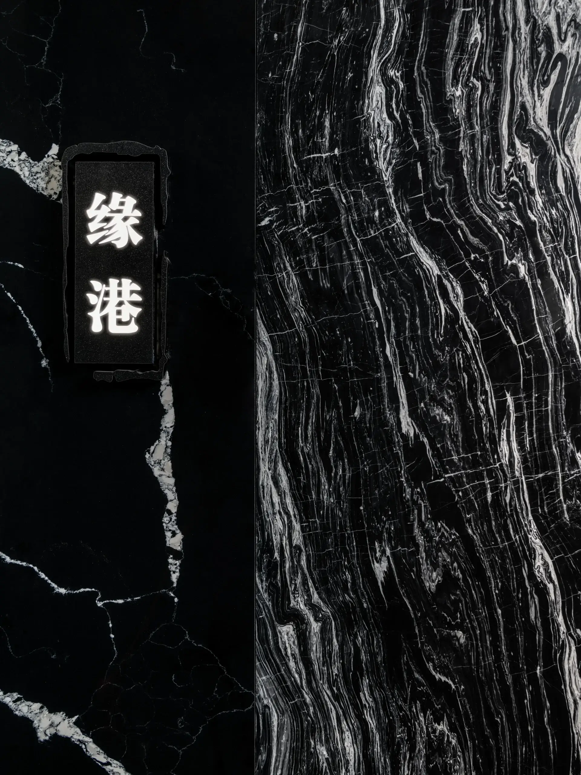 A black marble wall with a vertical panel of white Chinese characters on the left side, and a contrasting lighter veined marble pattern on the right.